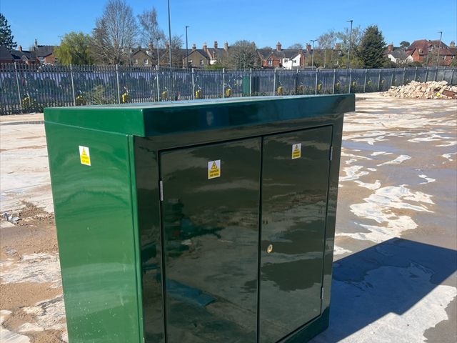 Closed green fibreglass electrical supply enclosure at Bicester Village