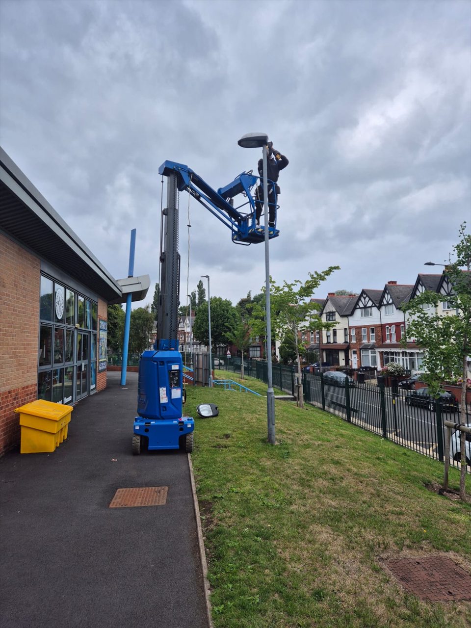 Engineer working on an external light from a blue access lift at a Birmingham school